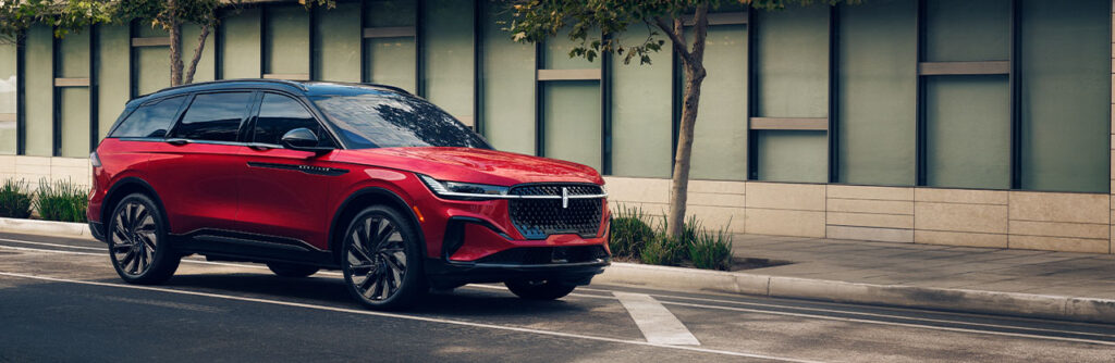 Red SUV parked on an urban street, with sleek design against a modern building backdrop.